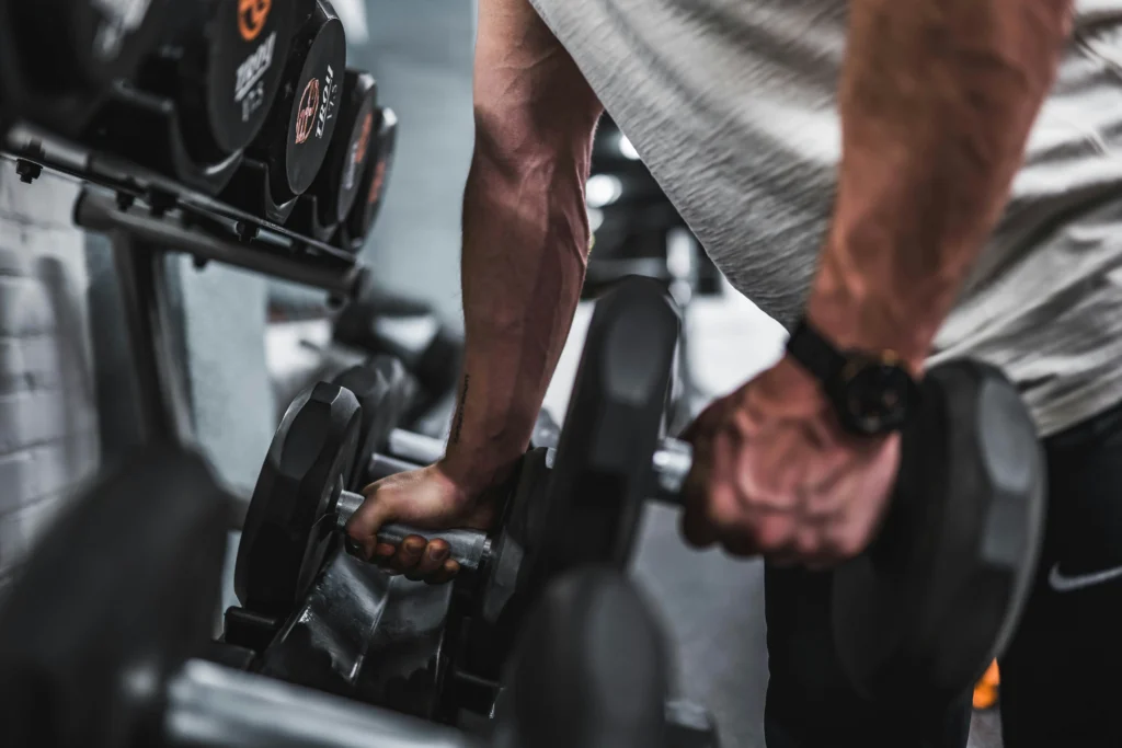 Close-up of athlete lifting heavy dumbbells in a gym, strength training exercise focused on muscle building, grip strength, and upper-body workout