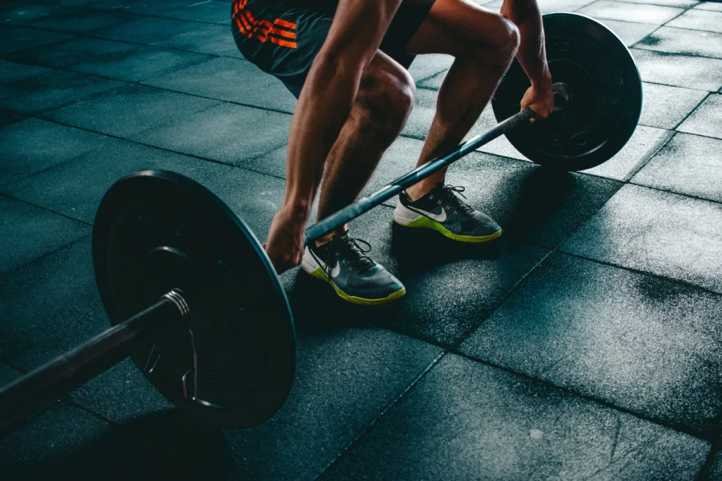 Athlete performing a barbell deadlift workout on gym floor, strength training exercise for muscle building, powerlifting, and full-body fitness